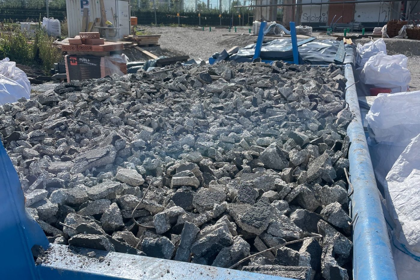 Abrollcontainer mit sortiertem Bauschutt auf einer Baustelle der EMMERR UG