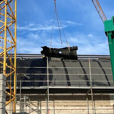 Kran hebt ein ausgebautes Dachelement von der Halle