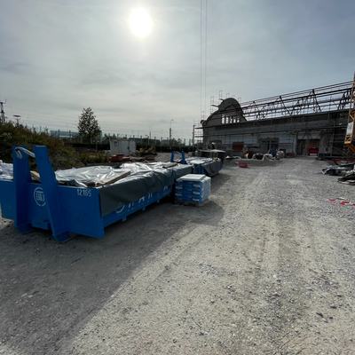 Baustellenfläche mit Abrollcontainern vor der Halle