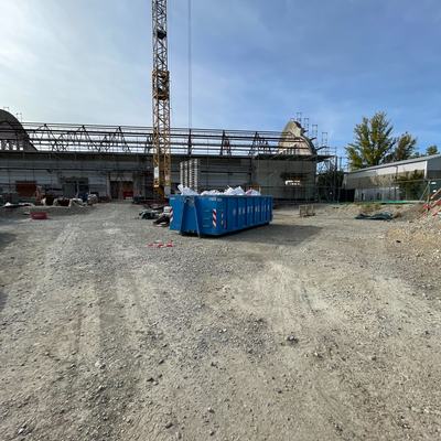 Kran und Container auf dem Baufeld vor der Halle
